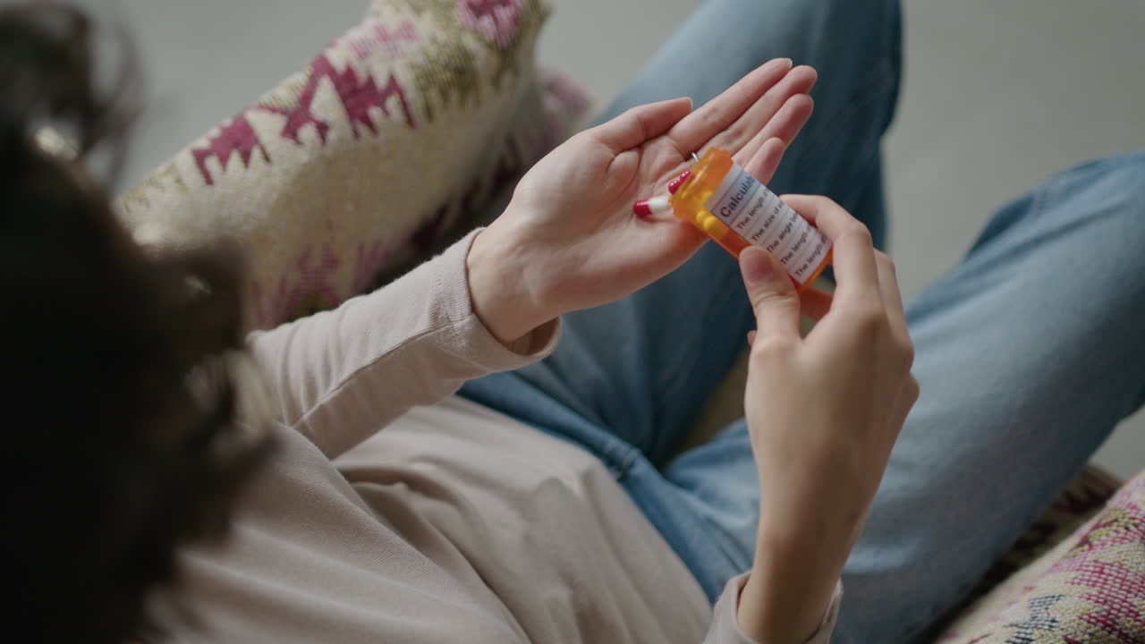 Woman Taking Pill from Prescription Bottle at Home