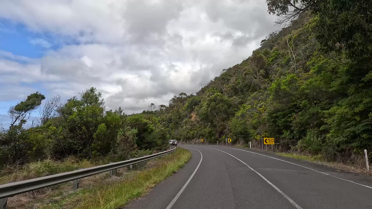 A 14-second video capturing a serene drive through lush greenery and winding roads under a partly cloudy sky