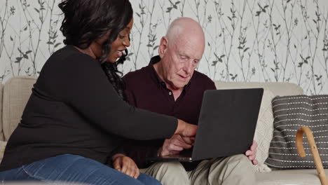 caregiver assisting senior man with laptop