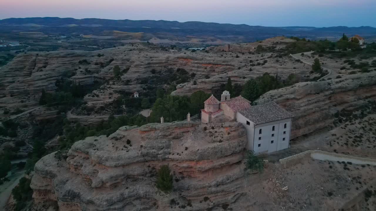 Aerial view of a church on a rocky hill at dusk