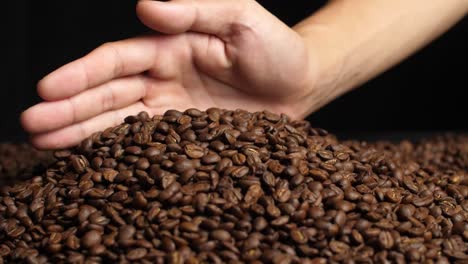 hand touching roasted coffee beans, slow motion