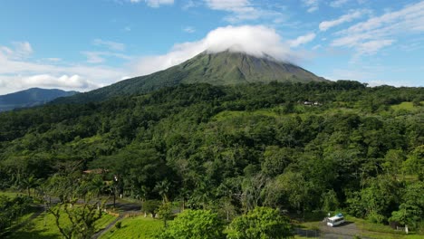 aerial view moving forward shot, scenic view of the landscape on the foothills of the arena volcano in costa rica, lenticular clouds on the volcano in the background