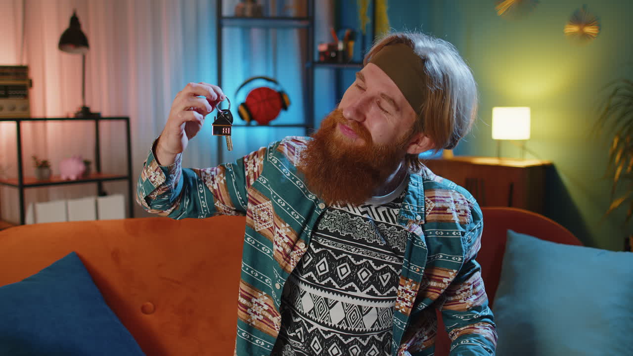 hippie hombre agente de bienes raíces mostrando las llaves de casa nueva apartamento, compra, alquiler de propiedad