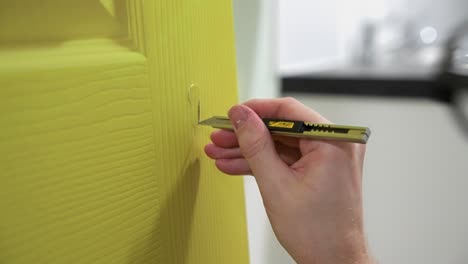 vinyl sticker installer using a small scalpel blade to carefully and accurately cut out parts of a door handle hole whilst applying the bright green stickers