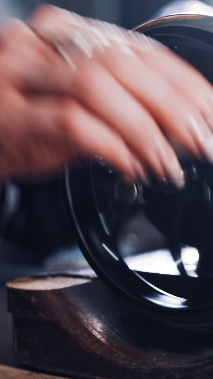 Close-up of woman's hand spinning the metal wheel of an old sewing machine. Seamstress is working on a black sewing machine in atelier. Craft and handmade concept. Vertical video