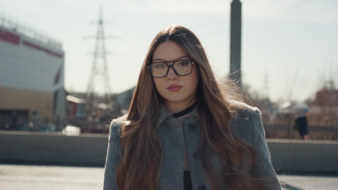 Signora elegante con stile urbano. Donna attenta alla moda che guarda con sicurezza vicino a un'area commerciale. Donna elegante che si sistema gli occhiali mentre si gode la vista della città di giorno fuori dal centro commerciale.