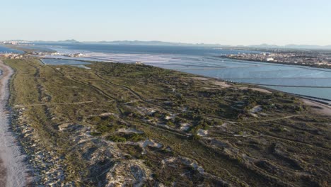 Downwards-panning-shot-of-dunes-with-saltlakes-in-the-background-in-Spain-during-golden-hour