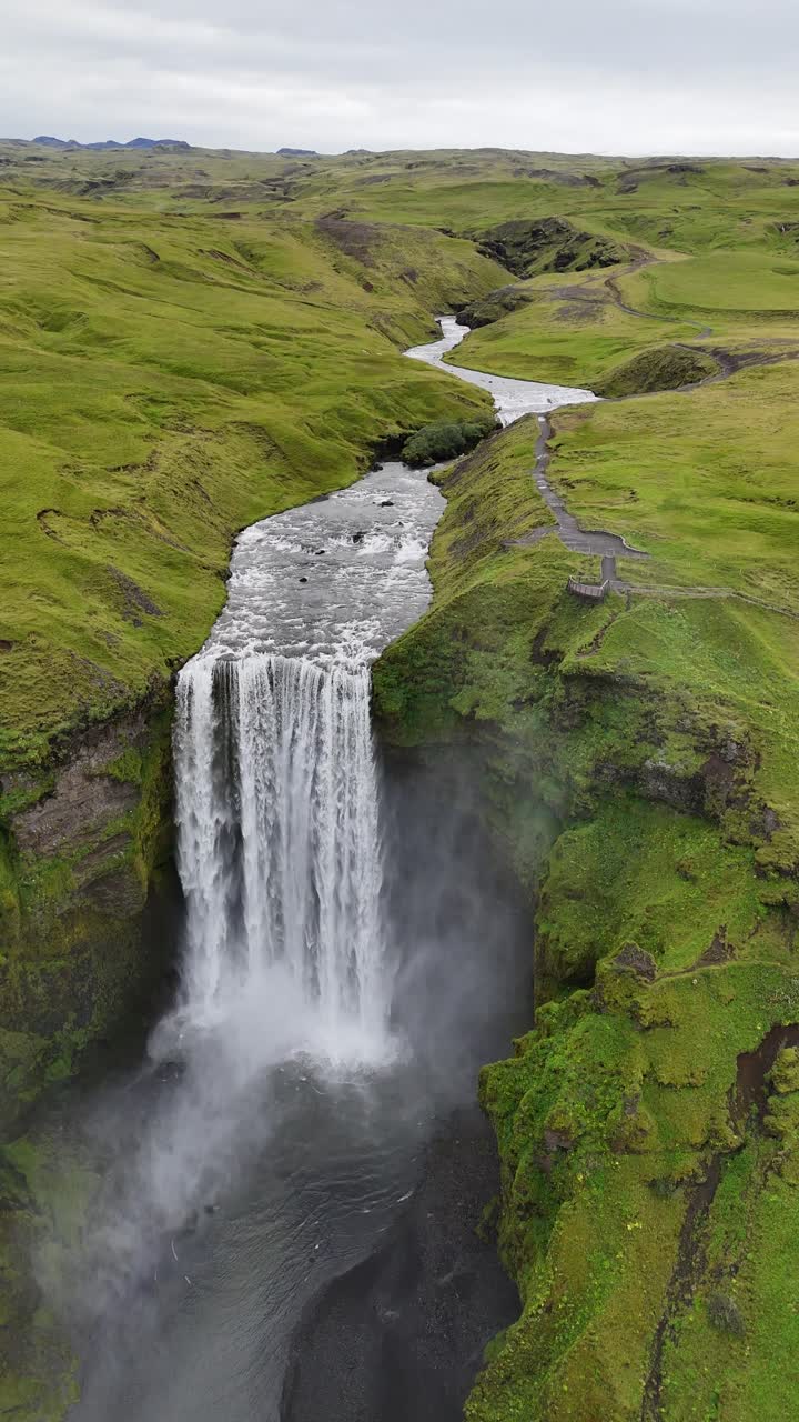 Slow motion vertical video flying over the Seljalandsfoss waterfall, in Iceland.