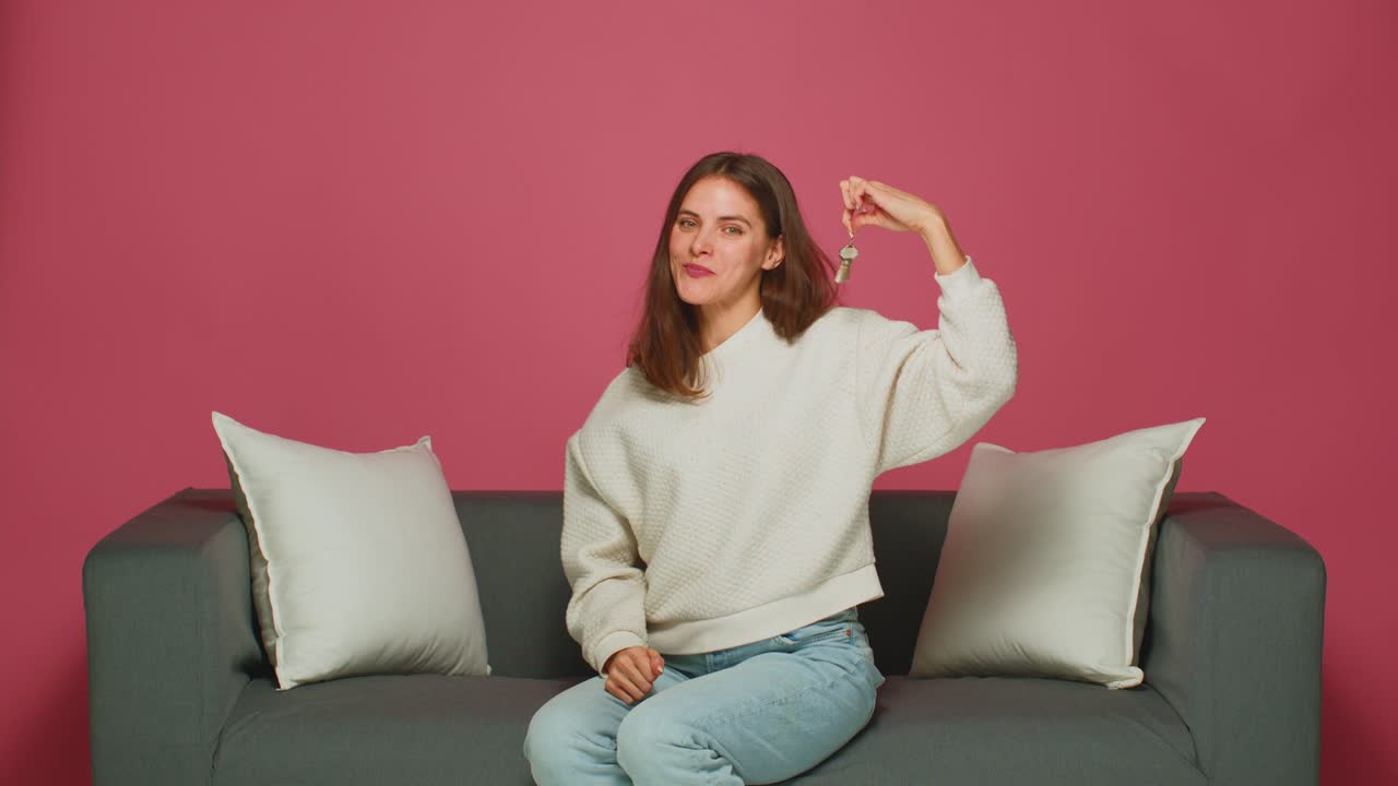 행복한 여성은 집 아파트의 열를 들고, 자랑스러운 집주인은 새로운 아파트 열를 보여주고, 소파에 앉아 있습니다. 유리한 주택담보대출율