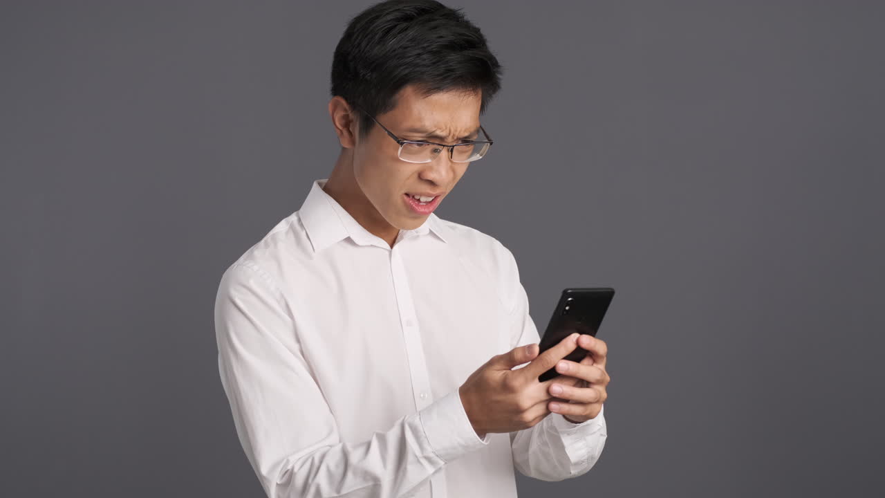Asian man using smartphone and getting angry.