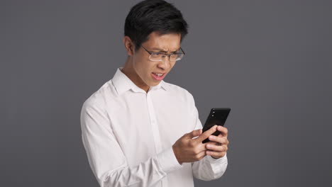 asian man using smartphone and getting angry.