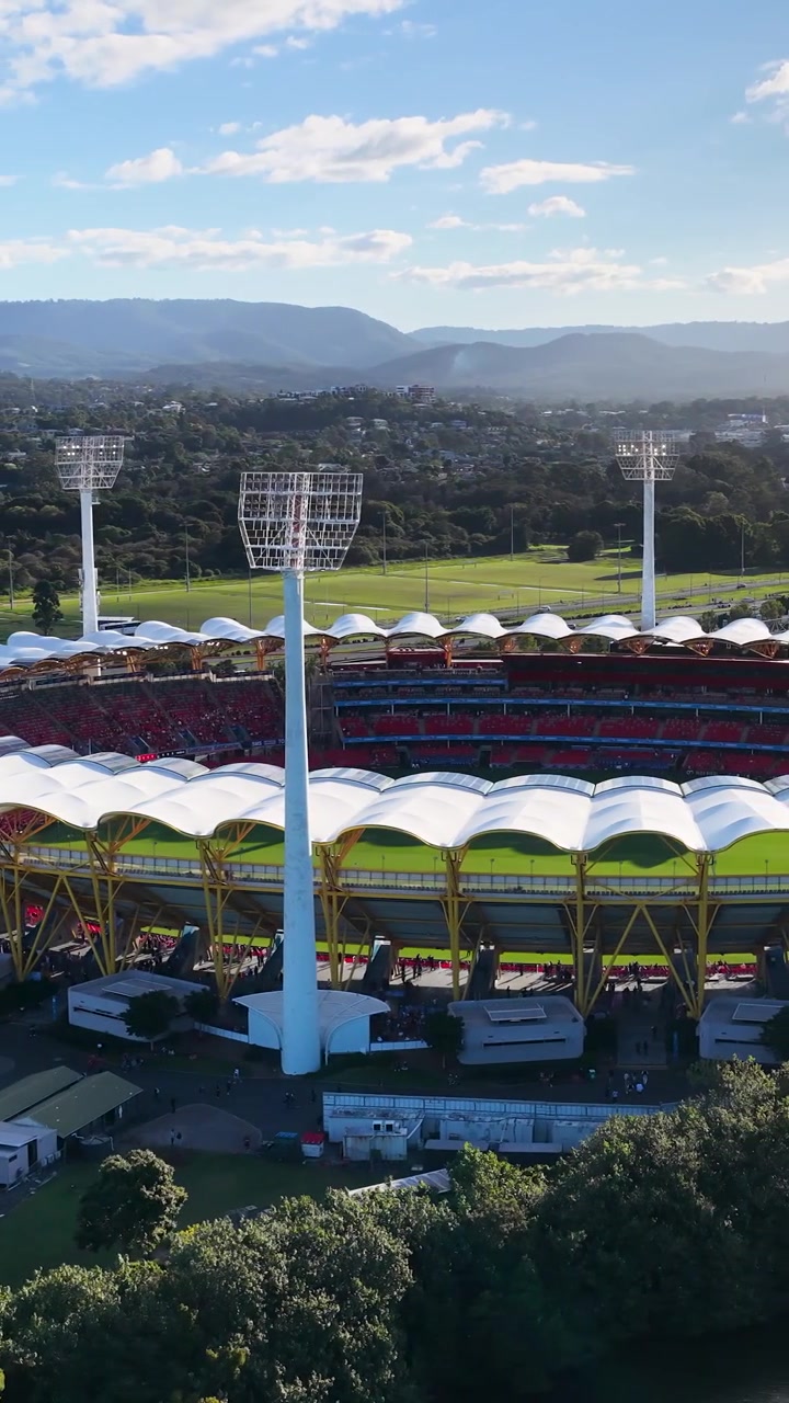 High angle drone shot of a large outdoor sports arena under a clear blue sky.