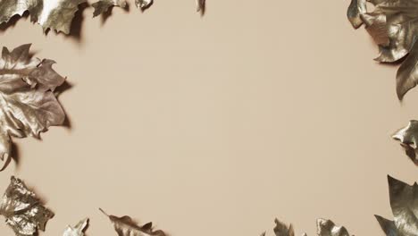 video of halloween autumn metallic leaves with copy space on yellow background