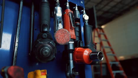 wrench impact tools hangin on a blue wall in a auto repair garage