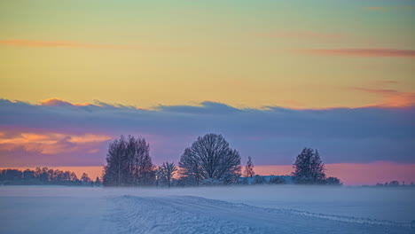 Picturesque-time-lapse-shot-of-wooden-house-surrounded-by-trees-covered-in-snow-and-icy-winds-blowing-from-morning-to-evening