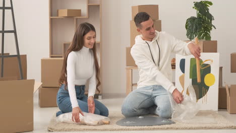 young couple moving into new house sitting on floor and assembling coffee table together