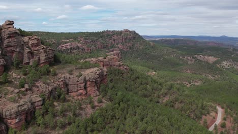 Aerial-view-of-red-sandstone-mountains-sorrounded-by-pine-forest-in-Albarracin,-Teruel