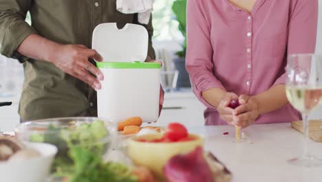 african american couple cooking and dumping waste in kitchen