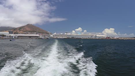 Un-Disparo-Desde-La-Parte-Trasera-De-Un-Catamarán-Que-Sale-De-La-Línea-De-Costa-Va-En-Ciudad-Del-Cabo,-Sudáfrica