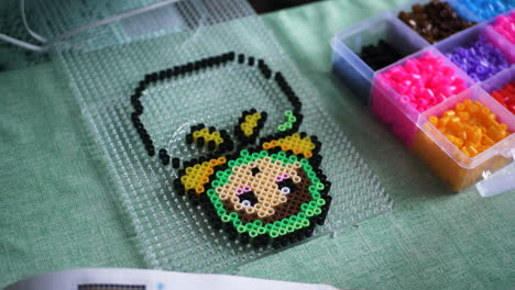 close up of female hands making colorful babushka design using ironing beads