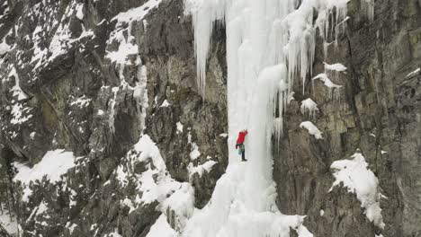 Aerial-one-lone-climber-scaling-frozen-cascade-Maineline,-Mount-Kineo-4K