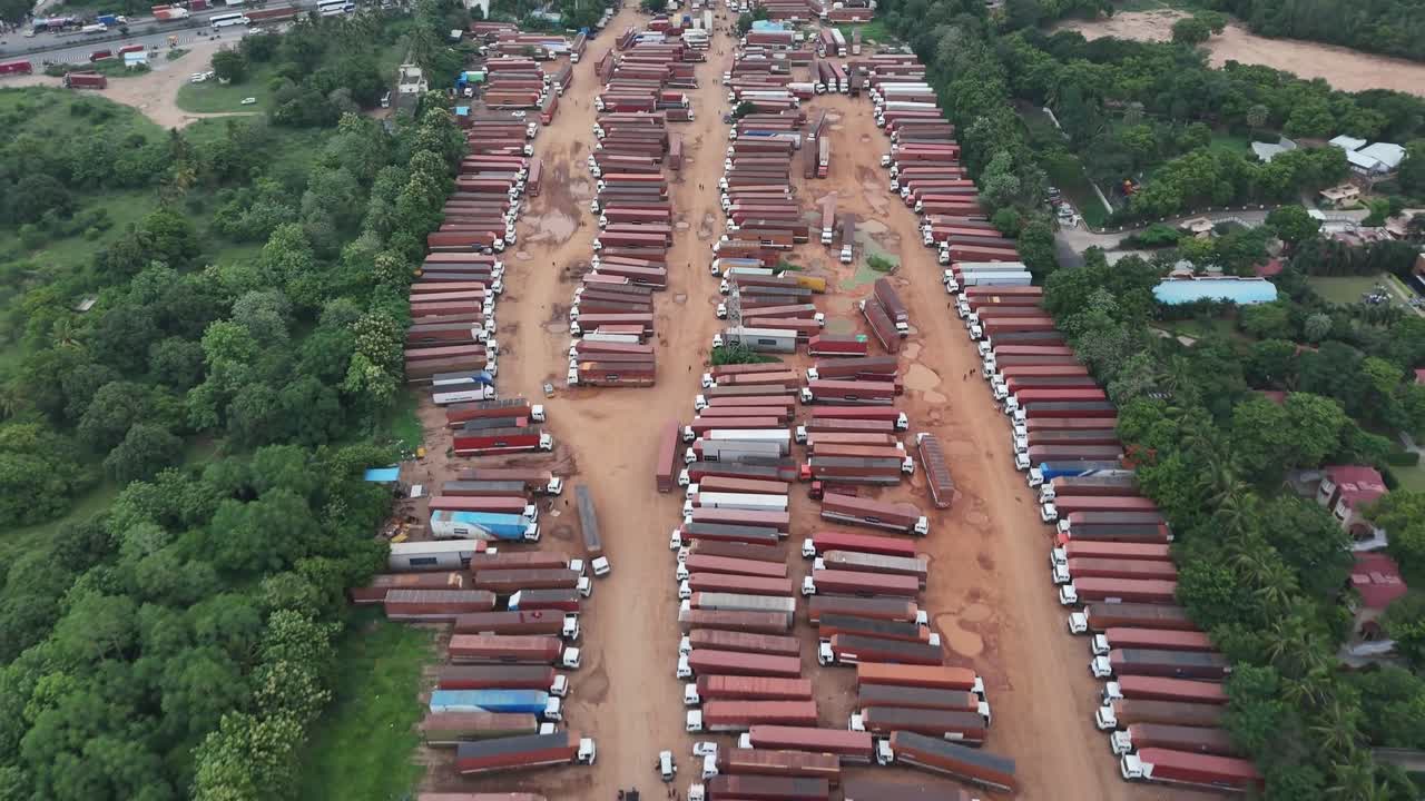 High-angle stock footage of a large, temporary truck depot. Hundreds of reddish semis sit idle, illustrating the scale of global supply chain and storage