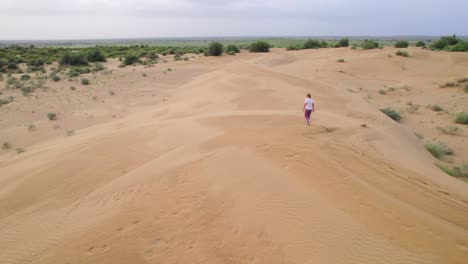 Vista-Aérea-De-Una-Mujer-Caminando-Por-El-Paisaje-Desértico