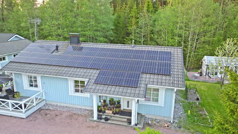 Wooden-house-powered-by-sunlight-collectors,-summer-sunrise-in-Finland---Aerial-view