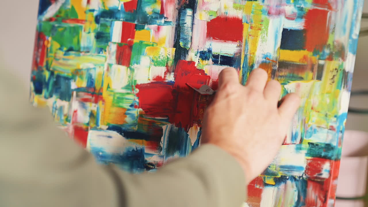las manos de un hombre irreconocible pintando con una espátula en un lienzo impresionista 2