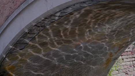 shimmering water reflections ripple under canal bridge arch stonework