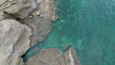 Drohnenaufnahmen-Von-Mediterranen-Klippen,-Die-Das-Leuchtend-Blaue-Meer-Zeigen,-Das-Die-Großen-Felsstrukturen-Umarmt