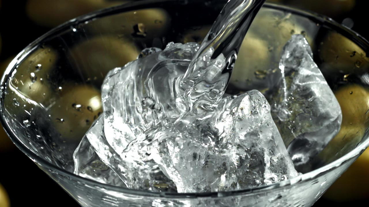Acqua limpida scorre su cubetti di ghiaccio in un bicchiere da Martini