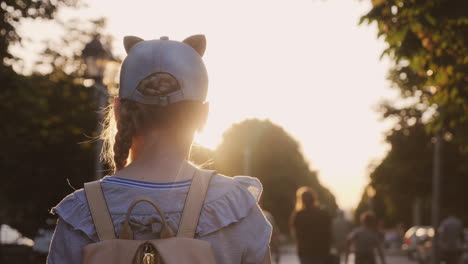 A-Girl-With-A-Backpack-Is-In-A-City-Park-Passersby-Go-By