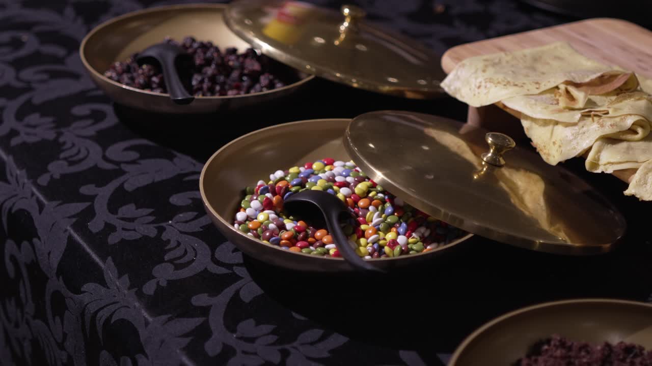 Brass bowls with colorful sweets and pastries on a luxurious black tablecloth