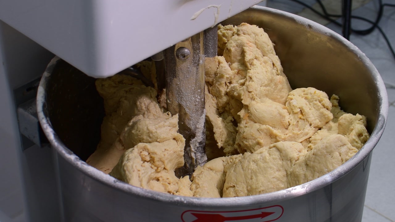 Industrial mixer kneading large batches of raw bread dough in a bakery