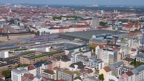 Great-aerial-top-view-flight-Munich-main-station-in-city-center,-German-Bavarian-Town-at-sunny-clear-sky-day-2023