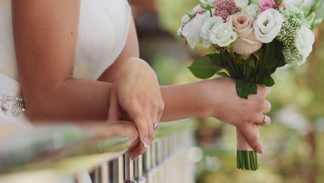 bride with fresh roses bouquet leans on balcony railing