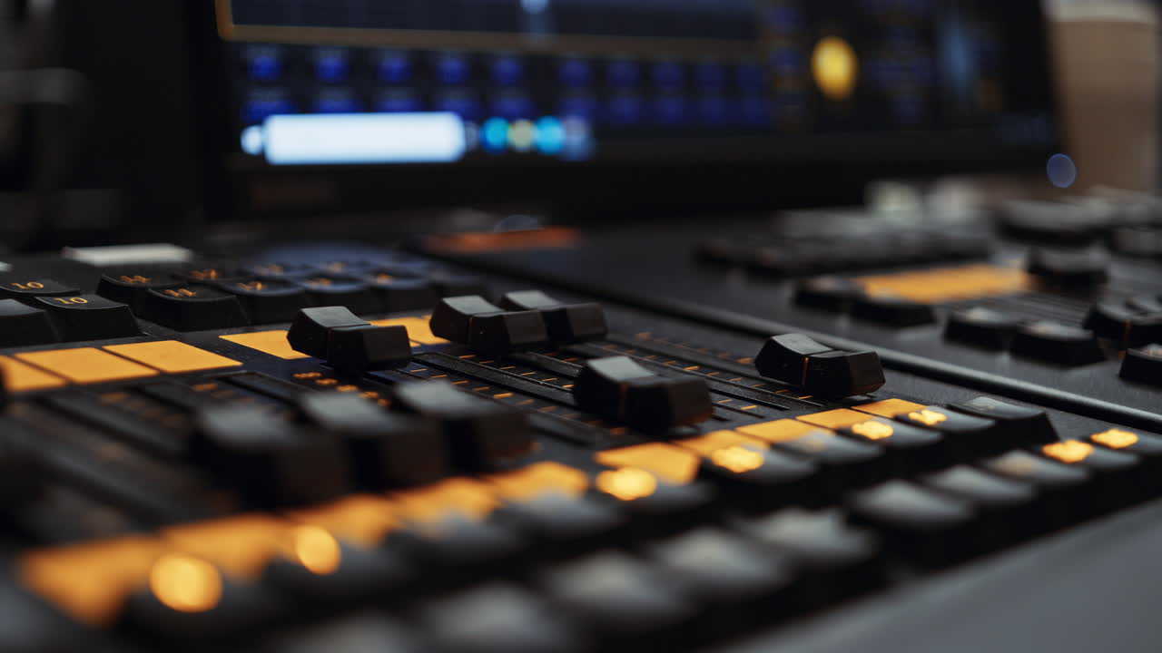 Two faders of a professional dmx lighting control desk console panel being turned down, dimming lights