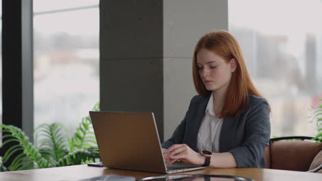 Una-Jefa-Exitosa-Está-Trabajando-Con-Una-Computadora-Portátil-En-Una-Oficina-Moderna.-Una-Dama-Bonita-Está-Escribiendo-Un-Mensaje-En-El-Chat-De-Trabajo.