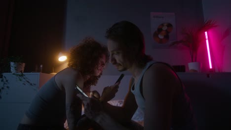 couple using phones in a bedroom at night