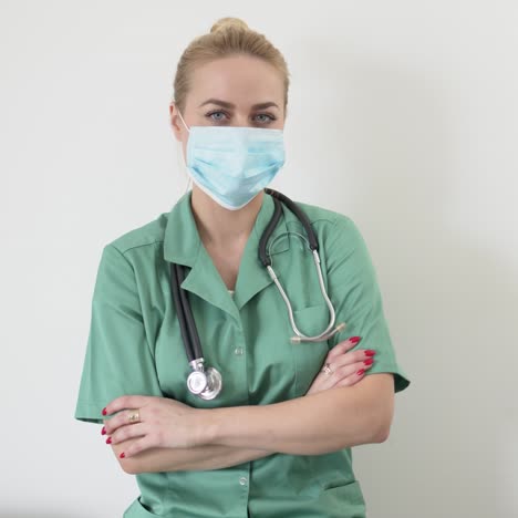 retrato de una joven doctora adulta con un abrigo de doctor verde y una máscara médica