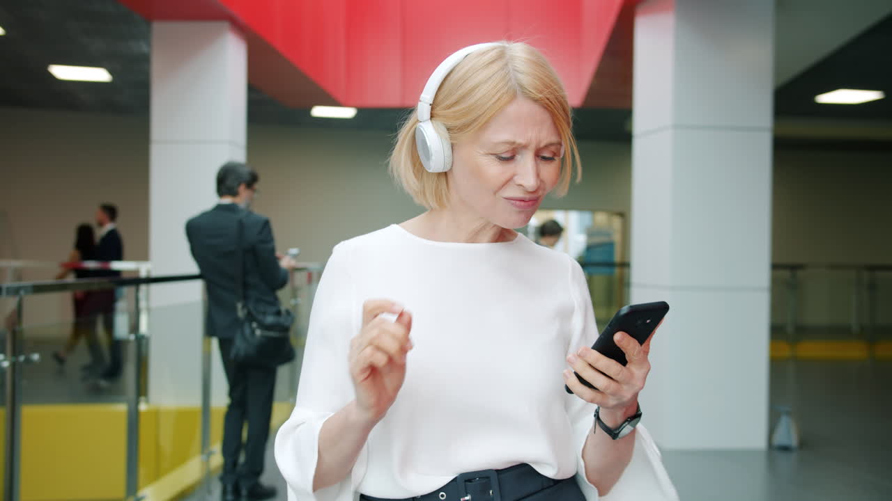 Businesswoman using smartphone in office hallway