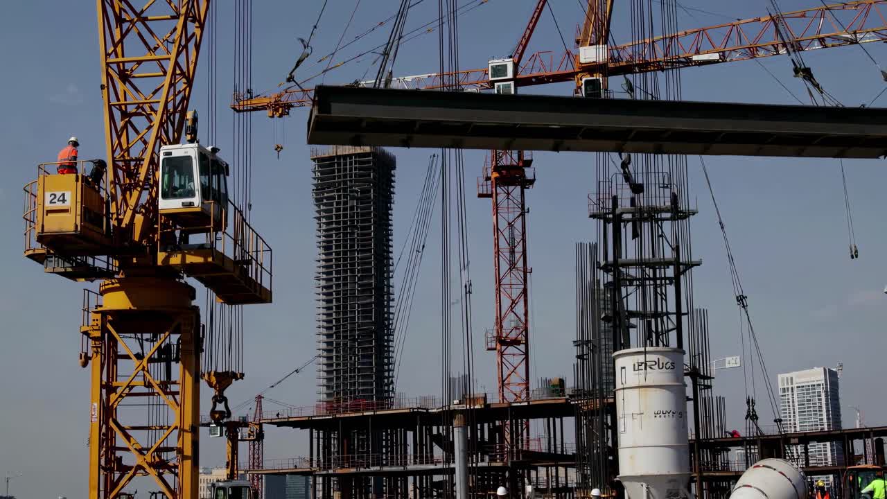 Dynamic video of a construction site with cranes and workers, captured from a low angle