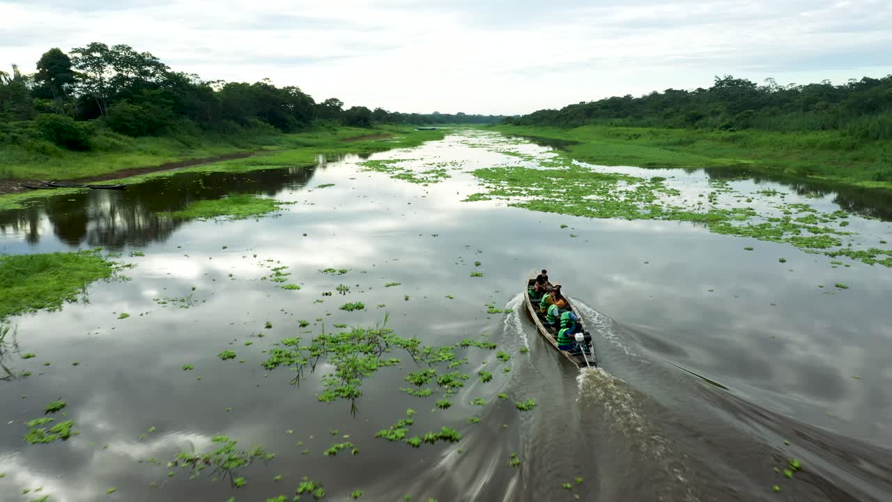gente en barco navegando por el río amazonas en perú - toma aérea siguiente