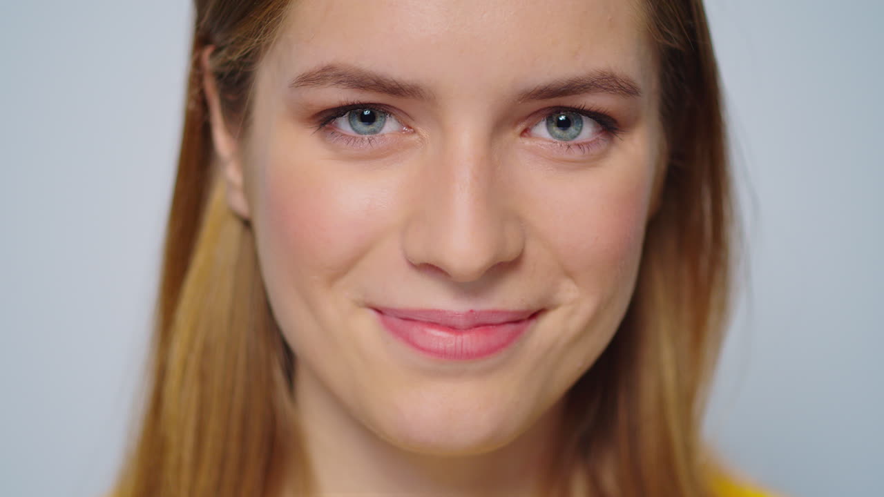 Closeup smiling attractive woman looking at camera on grey background.
