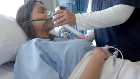 paciente femenina diversa en una cama de hospital y médico femenino poniéndole una máscara de oxígeno, cámara lenta