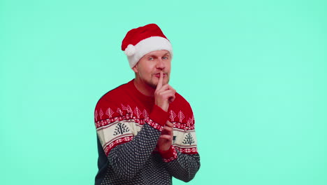 Der-Mann-Trägt-Einen-Roten-Weihnachtspullover,-Drückt-Den-Zeigefinger-An-Die-Lippen-Und-Macht-Ein-Zeichen-Der-Stille,-Ein-Geheimnis