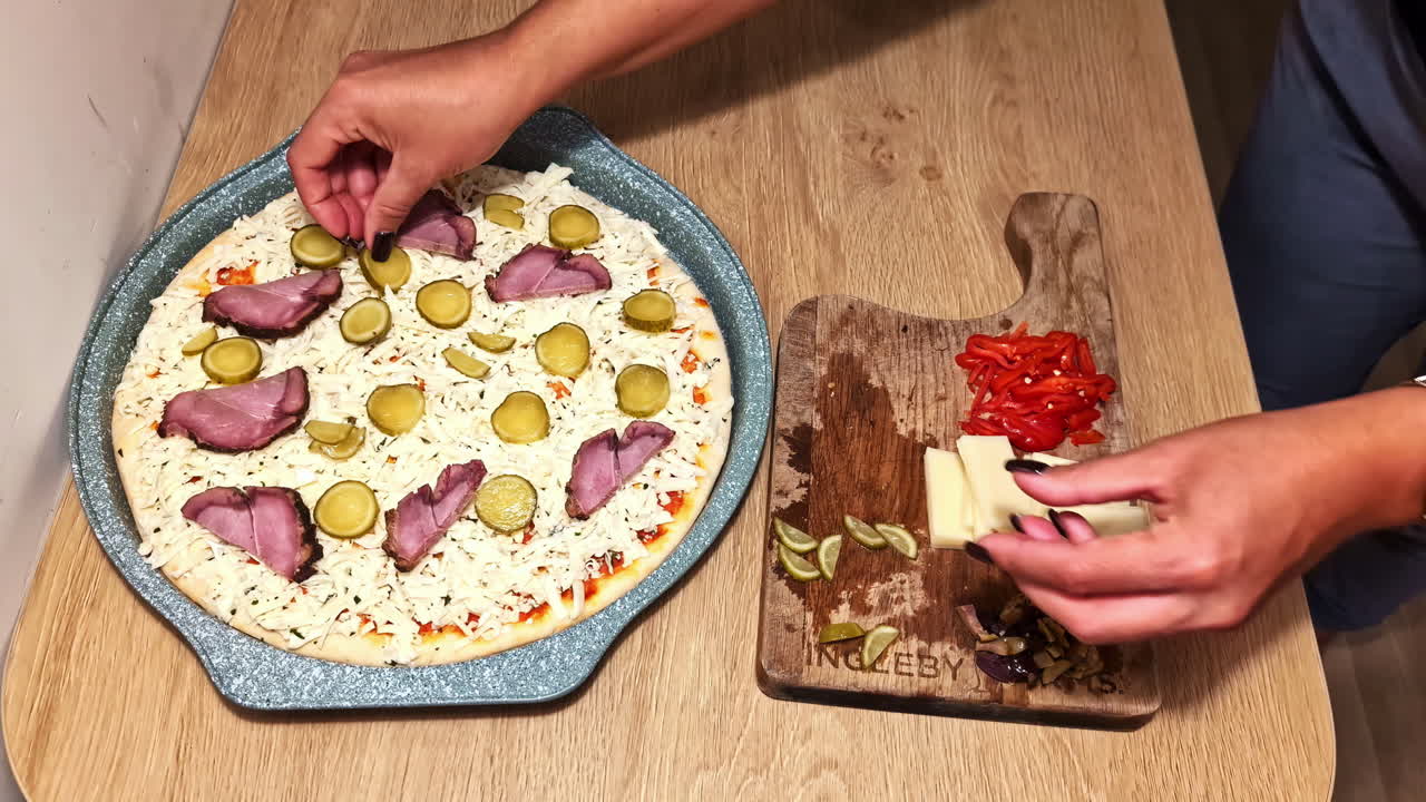Homemade pizza being topped with fresh ingredients in a warm and casual kitchen setting.