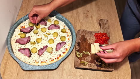 homemade pizza being topped with fresh ingredients in a warm and casual kitchen setting.