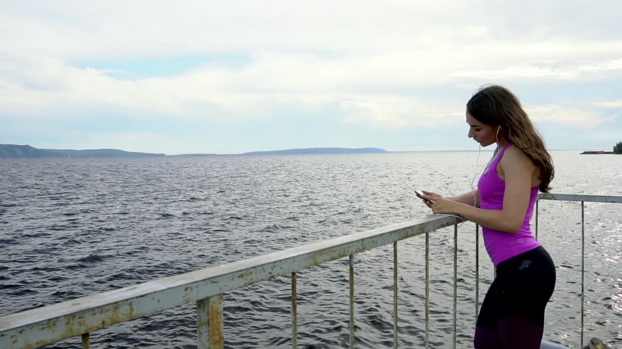 mujer disfrutando de una vista junto al río mientras escucha música